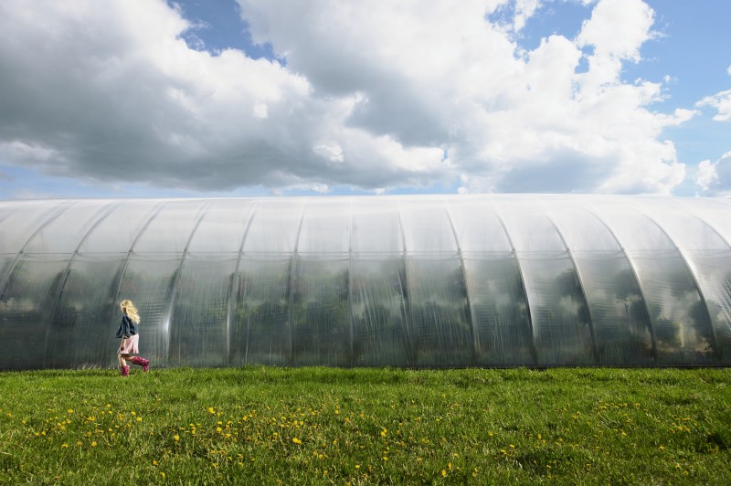 Girl Walking in Front of a Greenhouse